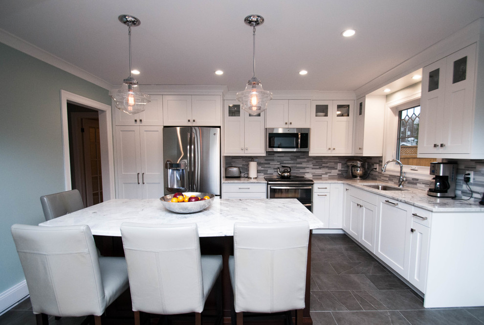 Mid-sized transitional l-shaped ceramic tile and gray floor eat-in kitchen photo with an undermount sink, shaker cabinets, white cabinets, quartzite countertops, gray backsplash, stone tile backsplash, stainless steel appliances and an island