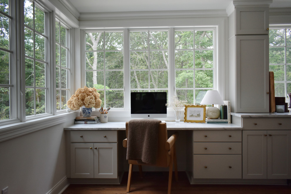 Example of a transitional built-in desk medium tone wood floor and brown floor home office design in New York with white walls