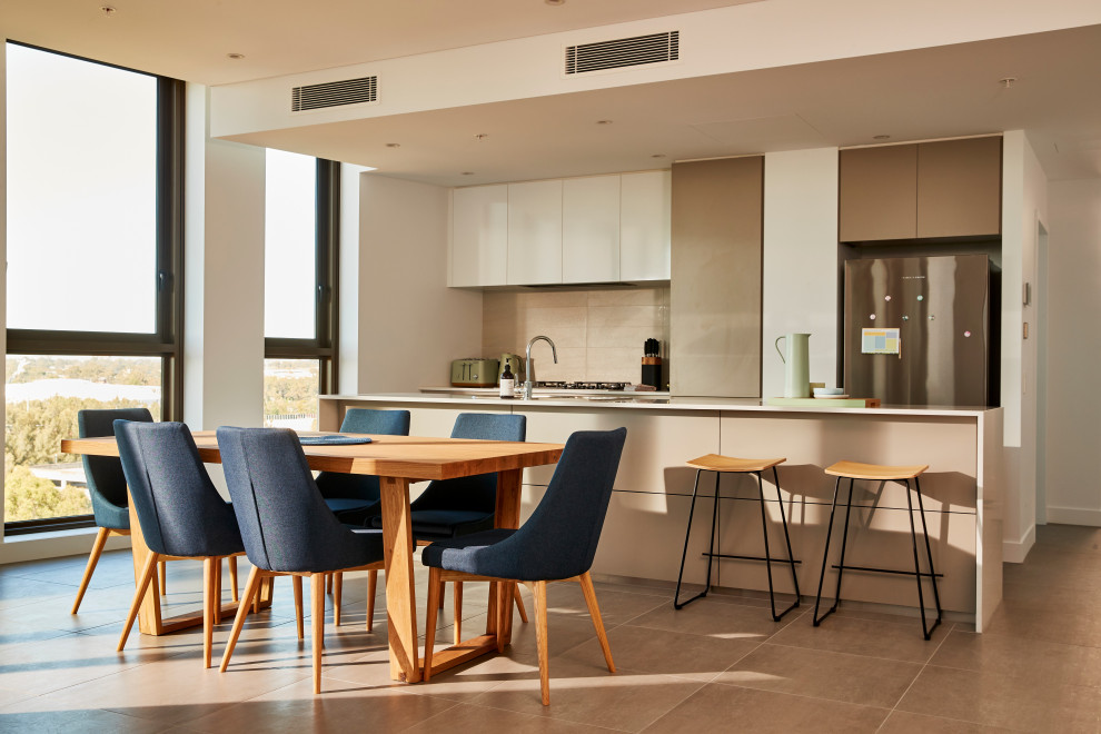 This is an example of a large contemporary galley eat-in kitchen in Melbourne with an undermount sink, grey cabinets, quartz benchtops, white splashback, ceramic splashback, stainless steel appliances, ceramic floors, with island, white benchtop, flat-panel cabinets and brown floor.