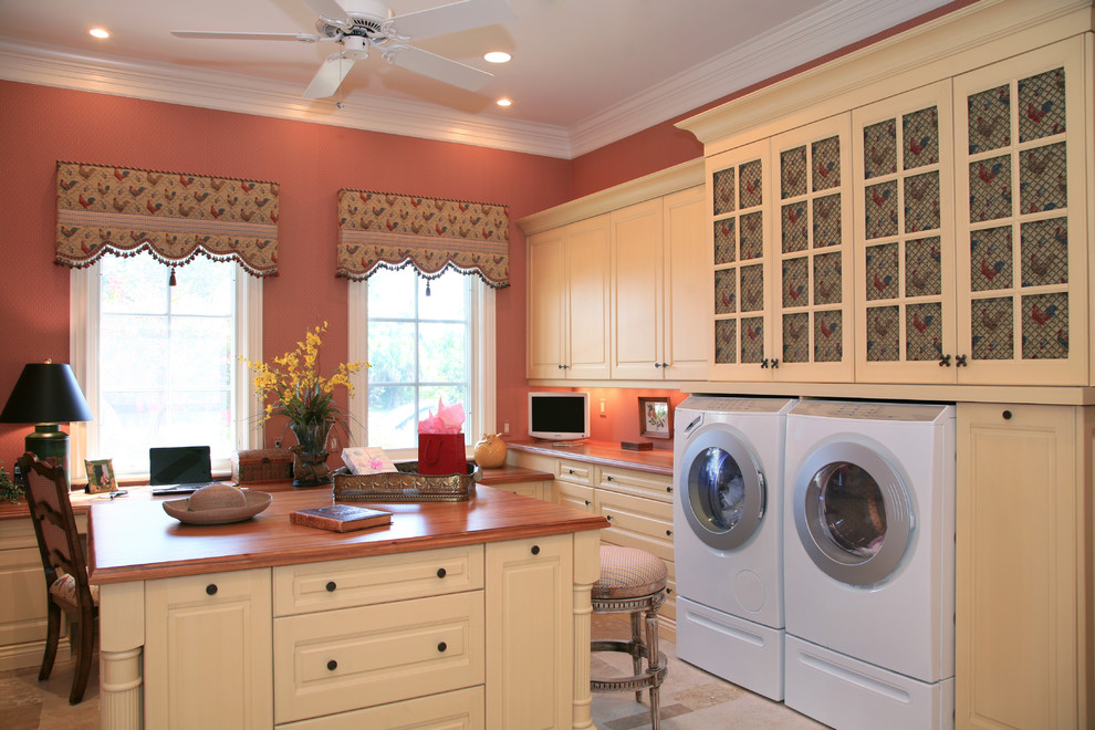 This is an example of a traditional laundry room in Miami with pink walls and white cabinets.