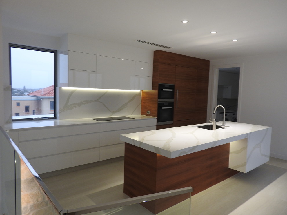 Photo of a large contemporary single-wall kitchen pantry in Gold Coast - Tweed with an undermount sink, flat-panel cabinets, medium wood cabinets, marble benchtops, white splashback, marble splashback, stainless steel appliances, beige floor, ceramic floors and with island.