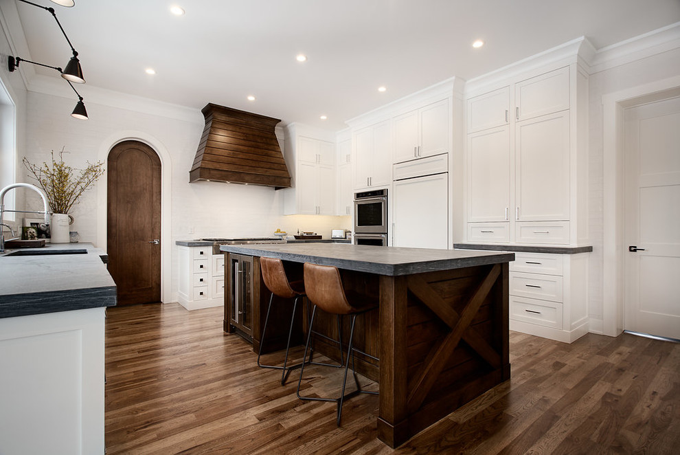 Inspiration for a large transitional dark wood floor and brown floor enclosed kitchen remodel in Calgary with shaker cabinets, paneled appliances, an island, a single-bowl sink, white cabinets and white backsplash