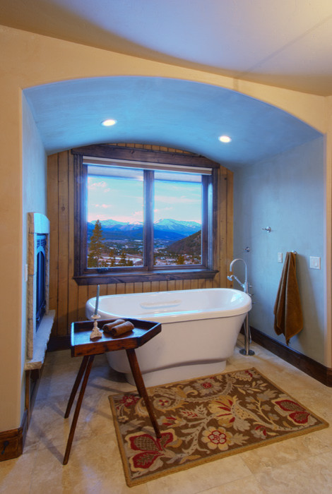 Inspiration for a large rustic master travertine floor and beige floor freestanding bathtub remodel in Orange County with beige walls
