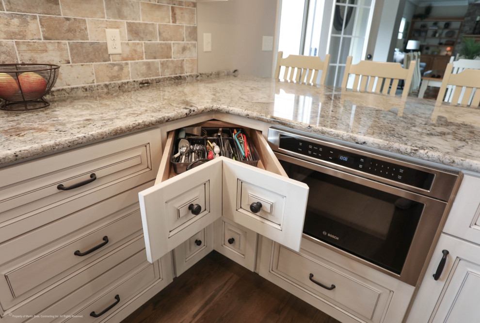 This is an example of a large traditional u-shaped kitchen pantry in Other with an undermount sink, raised-panel cabinets, white cabinets, granite benchtops, porcelain splashback, stainless steel appliances, medium hardwood floors and with island.