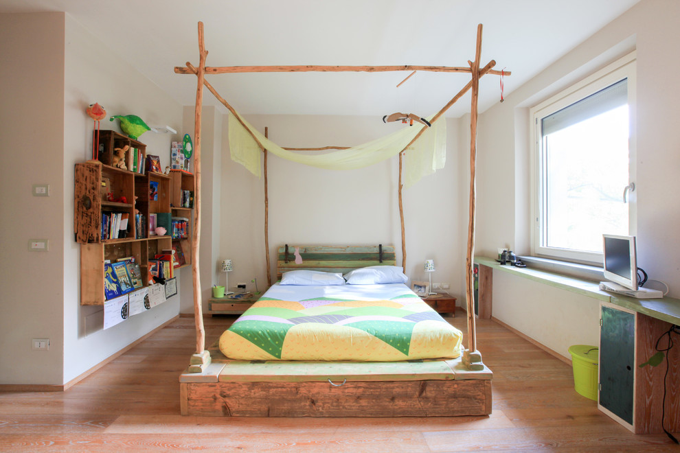 This is an example of a mid-sized country gender-neutral kids' bedroom for kids 4-10 years old in Milan with beige walls, medium hardwood floors and brown floor.