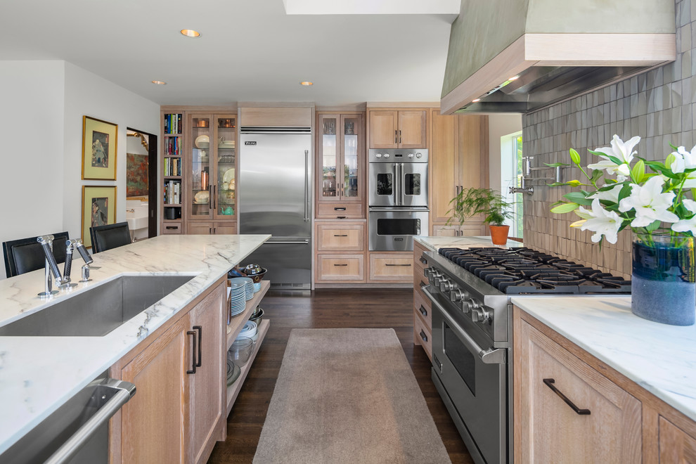This is an example of a large contemporary l-shaped open plan kitchen in Seattle with an undermount sink, recessed-panel cabinets, light wood cabinets, marble benchtops, grey splashback, cement tile splashback, stainless steel appliances, dark hardwood floors, with island and brown floor.