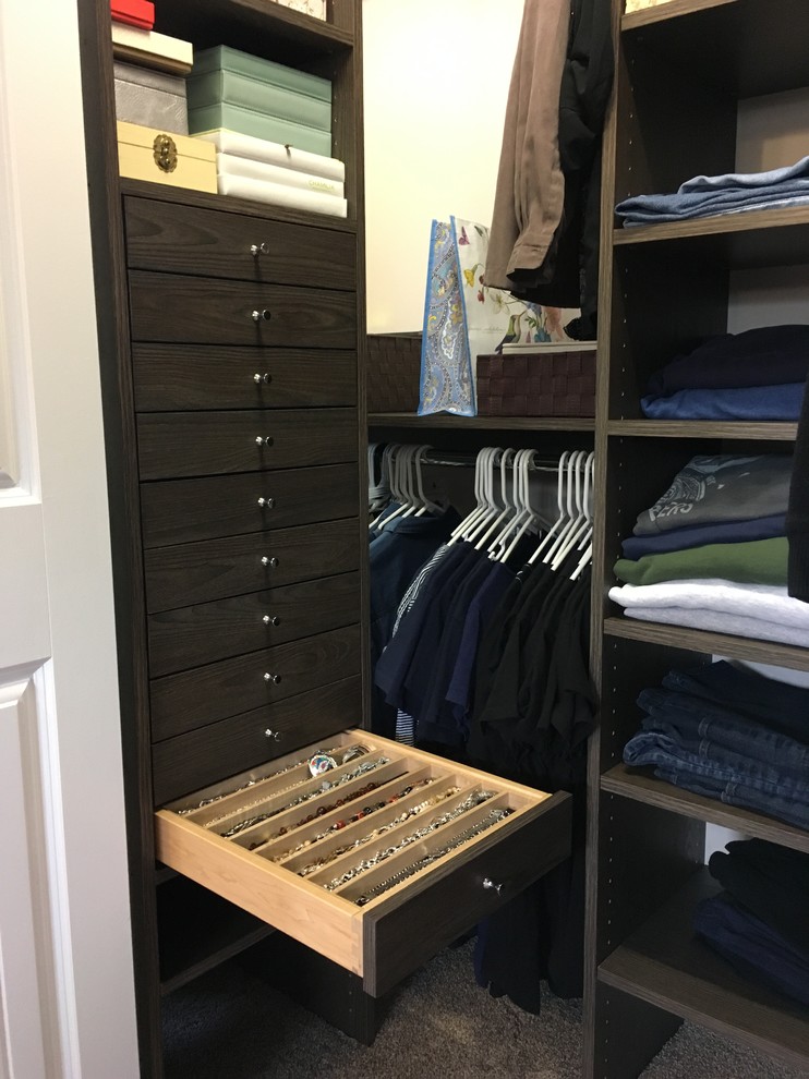 Design ideas for a small transitional gender-neutral built-in wardrobe in Other with flat-panel cabinets, dark wood cabinets and carpet.
