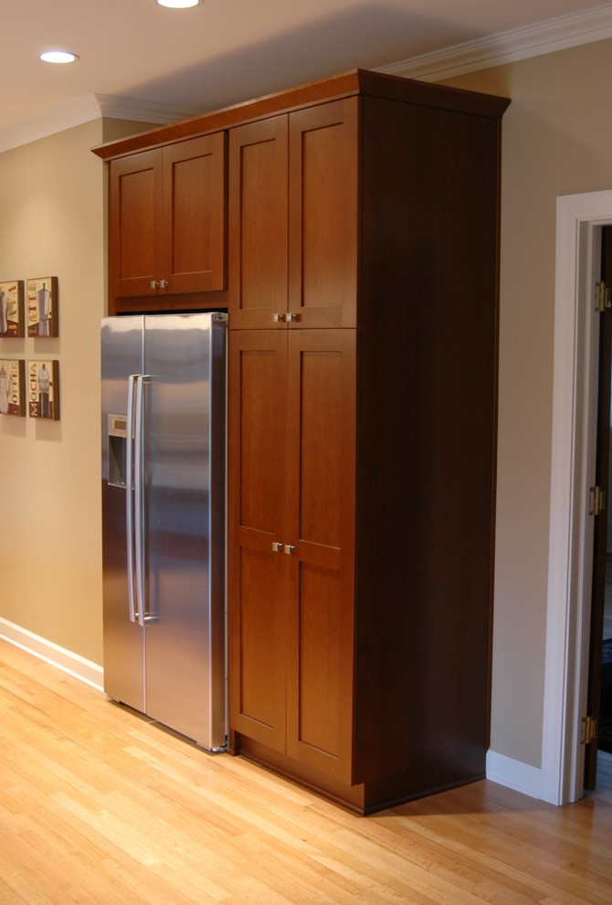 Enclosed kitchen - small transitional l-shaped light wood floor enclosed kitchen idea in Chicago with an undermount sink, shaker cabinets, medium tone wood cabinets, quartz countertops, beige backsplash, porcelain backsplash, stainless steel appliances and an island