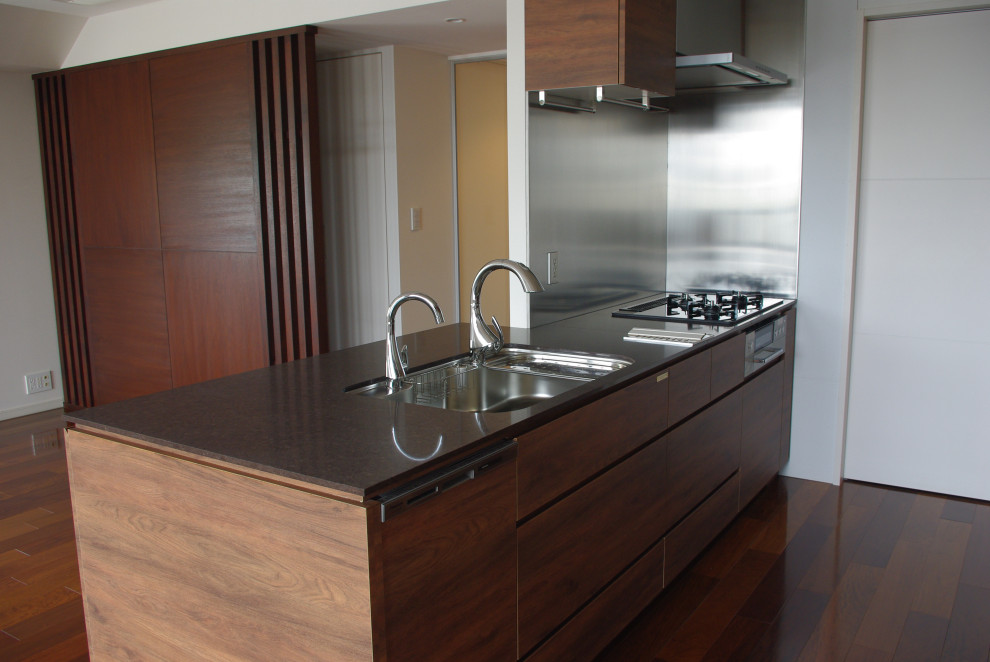 This is an example of a modern single-wall separate kitchen in Tokyo with an undermount sink, flat-panel cabinets, brown cabinets, quartz benchtops, grey splashback, stainless steel appliances, dark hardwood floors, brown floor, brown benchtop and wallpaper.