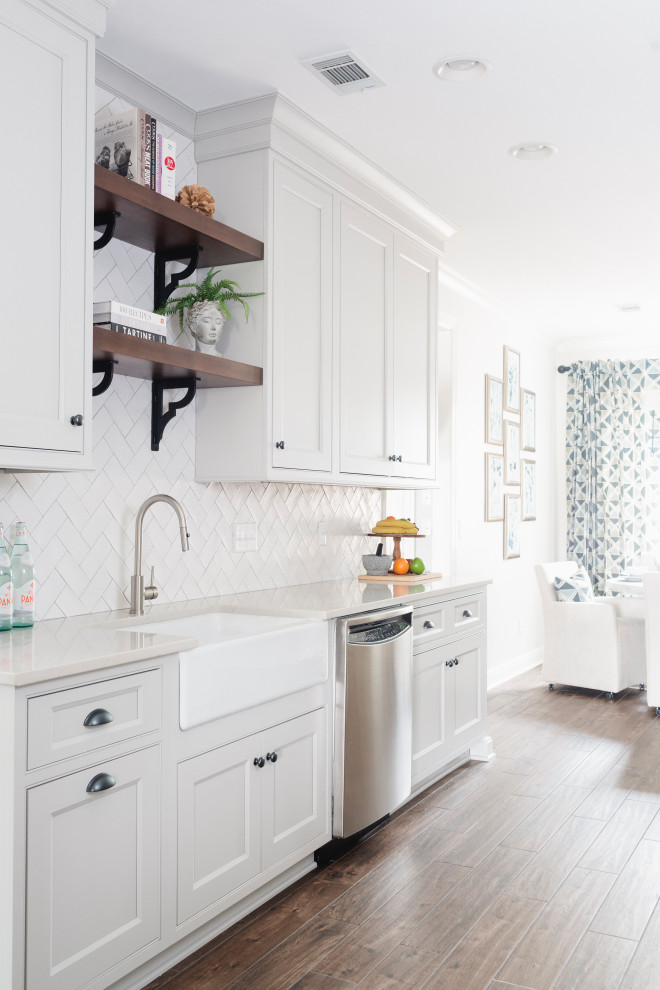 Inspiration for a mid-sized contemporary galley medium tone wood floor kitchen remodel in Birmingham with a farmhouse sink, recessed-panel cabinets, white cabinets, white backsplash, ceramic backsplash, stainless steel appliances, no island and white countertops