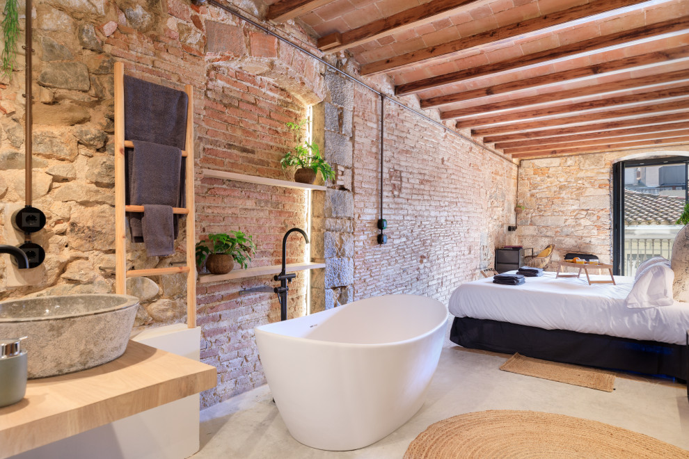 Imagen de dormitorio principal clásico renovado con suelo de cemento, suelo gris, vigas vistas y ladrillo