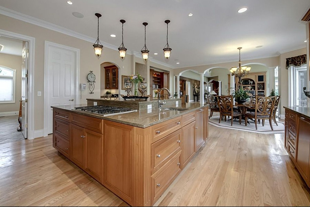 Example of a huge transitional l-shaped limestone floor and beige floor enclosed kitchen design in DC Metro with a double-bowl sink, recessed-panel cabinets, medium tone wood cabinets, granite countertops, multicolored backsplash, stainless steel appliances, a peninsula and ceramic backsplash