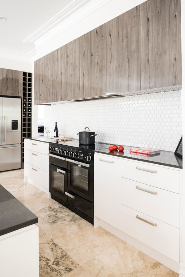 Expansive modern l-shaped open plan kitchen in Melbourne with an undermount sink, flat-panel cabinets, light wood cabinets, quartz benchtops, white splashback, mosaic tile splashback, black appliances, marble floors, with island and pink floor.