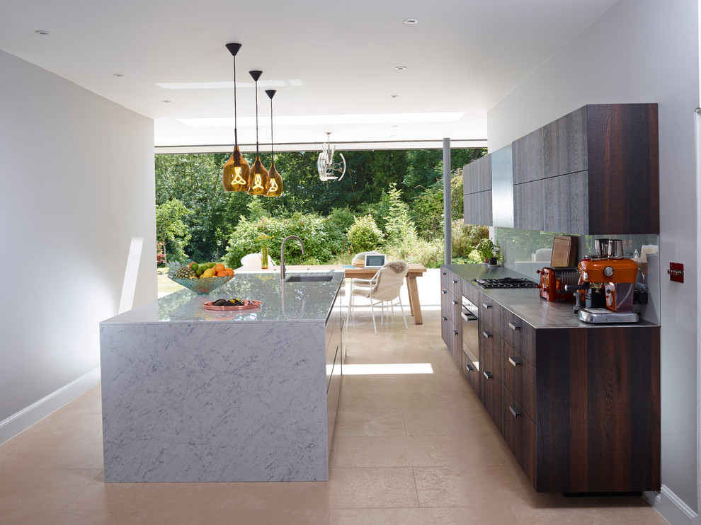 Design ideas for a contemporary galley eat-in kitchen in Devon with a single-bowl sink, glass sheet splashback, limestone floors, with island, flat-panel cabinets, dark wood cabinets, stainless steel benchtops, stainless steel appliances and grey splashback.