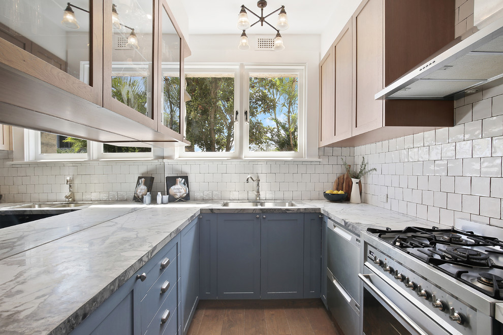 Small transitional u-shaped separate kitchen in Sydney with an undermount sink, shaker cabinets, blue cabinets, marble benchtops, white splashback, ceramic splashback, stainless steel appliances, dark hardwood floors, no island, brown floor and white benchtop.