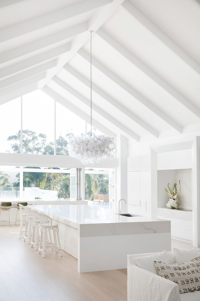 Inspiration for a large beach style galley eat-in kitchen in Sydney with an undermount sink, white cabinets, white splashback, panelled appliances, with island and white benchtop.