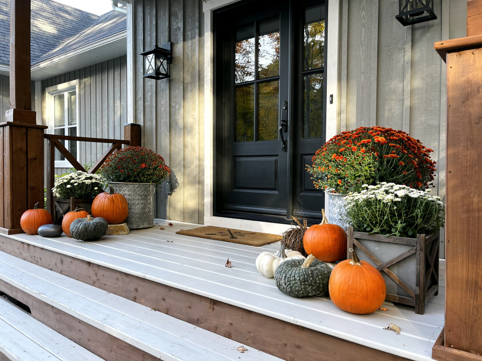На фото: веранда среднего размера на переднем дворе в стиле кантри с растениями в контейнерах, настилом, навесом и деревянными перилами с