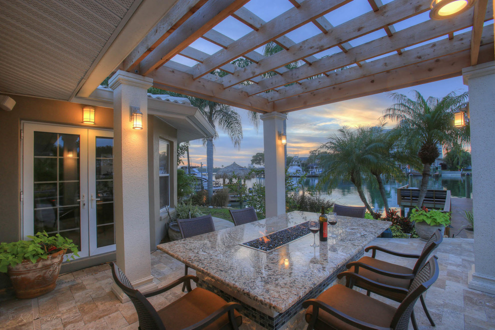 Inspiration for a mid-sized traditional backyard patio in Tampa with a fire feature, natural stone pavers and a pergola.