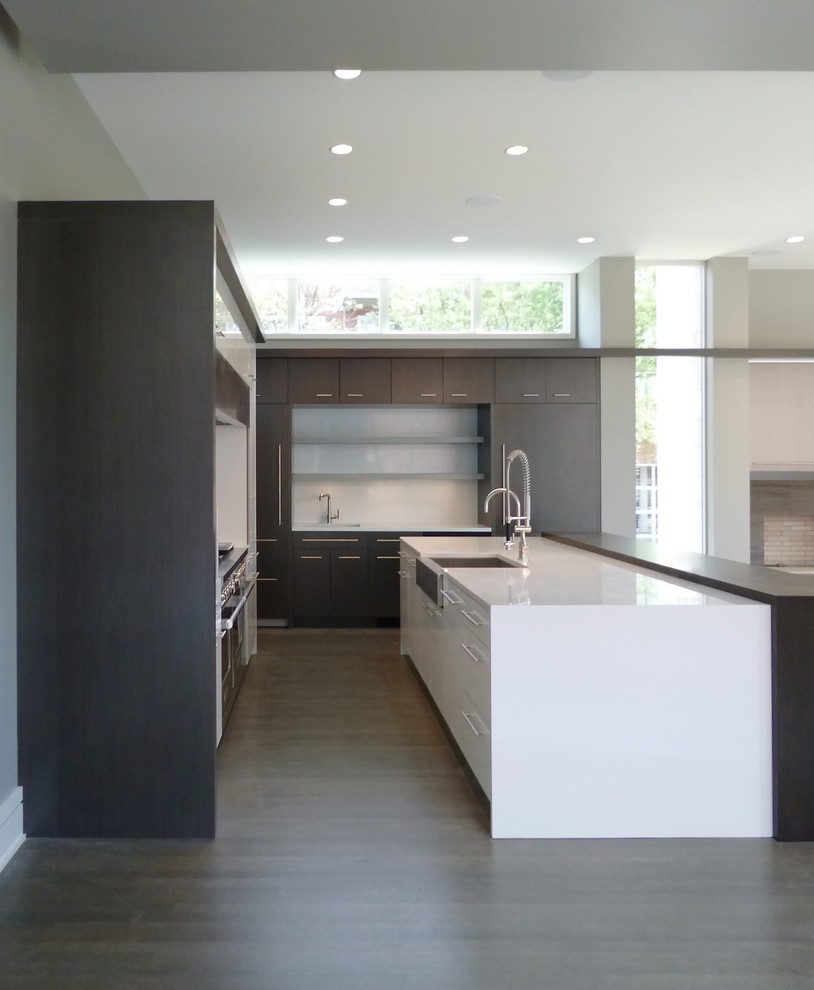 Design ideas for a mid-sized modern l-shaped open plan kitchen in Chicago with a farmhouse sink, flat-panel cabinets, quartz benchtops, white splashback, medium hardwood floors, with island, white cabinets, stone slab splashback, panelled appliances, brown floor and white benchtop.