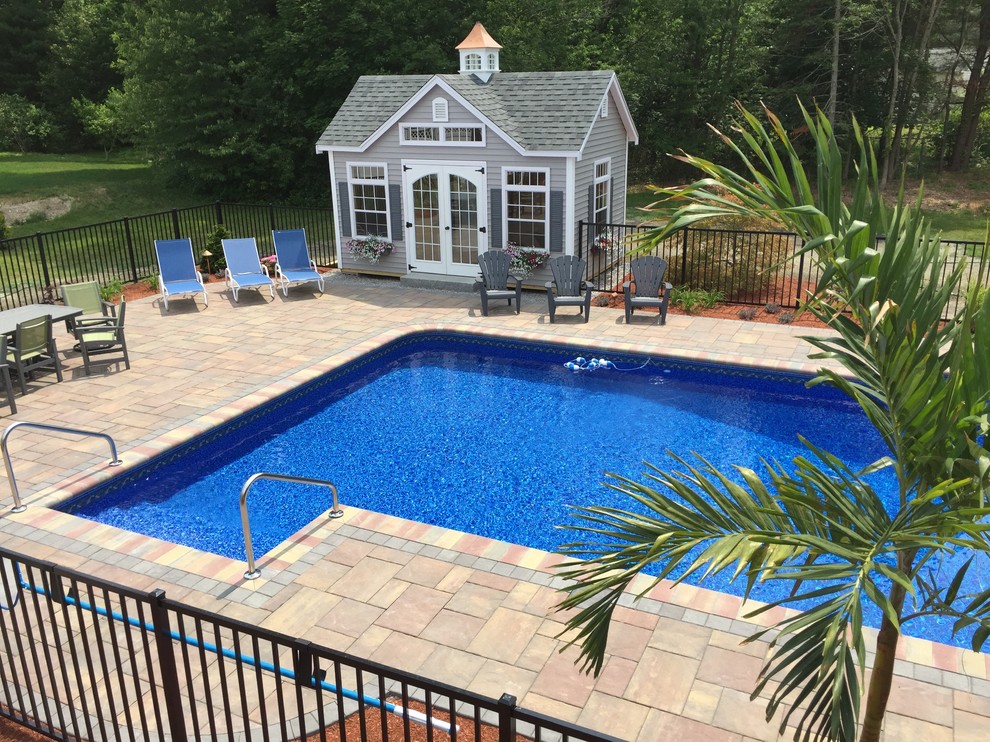 Photo of a large transitional backyard l-shaped natural pool in Boston with a pool house and concrete pavers.