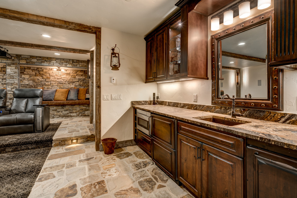 This is an example of a large country single-wall wet bar in Denver with an undermount sink, raised-panel cabinets, medium wood cabinets, granite benchtops, slate floors and beige floor.