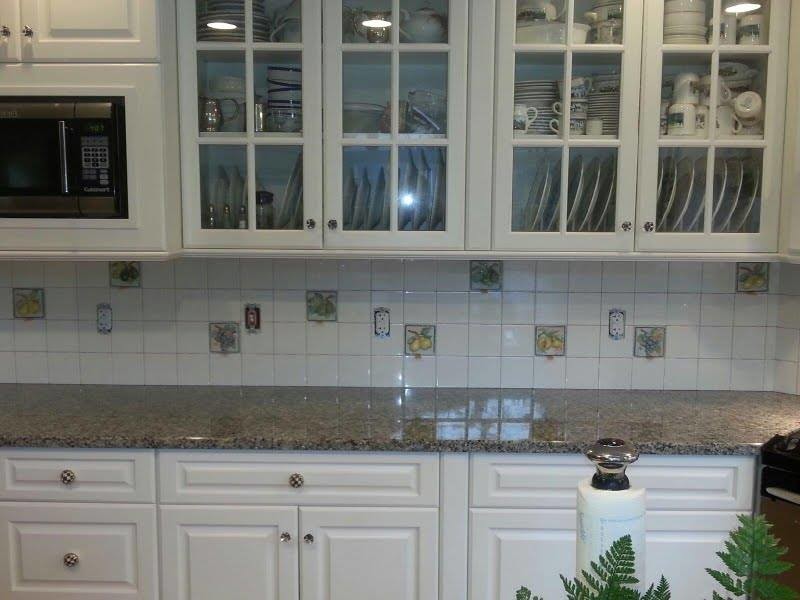 Example of a mid-sized single-wall kitchen design in Bridgeport with raised-panel cabinets, white cabinets, granite countertops, white backsplash, porcelain backsplash and black appliances