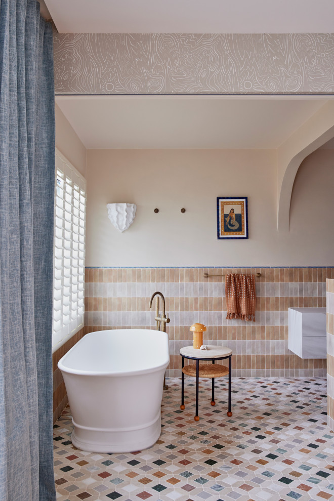 Photo of a large mediterranean master bathroom in Sydney with flat-panel cabinets, beige cabinets, a freestanding tub, a wall-mount toilet, multi-coloured tile, ceramic tile, beige walls, mosaic tile floors, a vessel sink, quartzite benchtops, multi-coloured floor, beige benchtops, an enclosed toilet, a single vanity, a freestanding vanity and recessed.