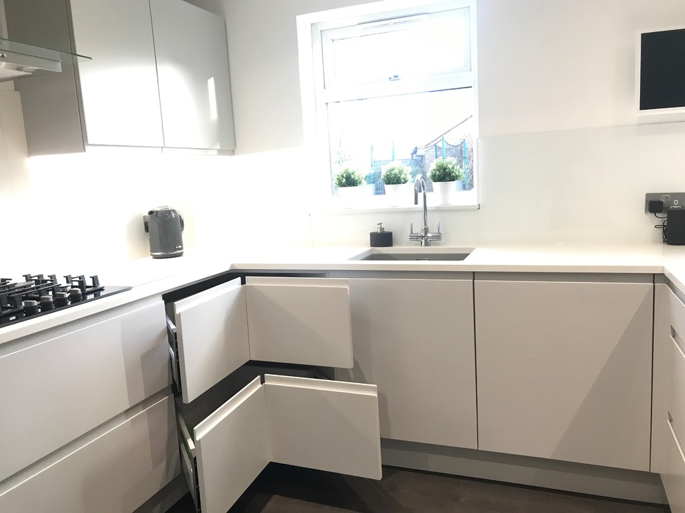 Mid-sized contemporary u-shaped separate kitchen in Buckinghamshire with an undermount sink, flat-panel cabinets, grey cabinets, quartzite benchtops, white splashback, glass sheet splashback, panelled appliances, vinyl floors, a peninsula, grey floor and white benchtop.
