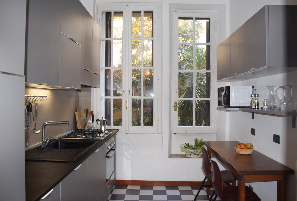 Immagine di una cucina lineare contemporanea chiusa e di medie dimensioni con lavello da incasso, ante lisce, ante grigie, top in superficie solida, pavimento con piastrelle in ceramica, pavimento multicolore e top nero