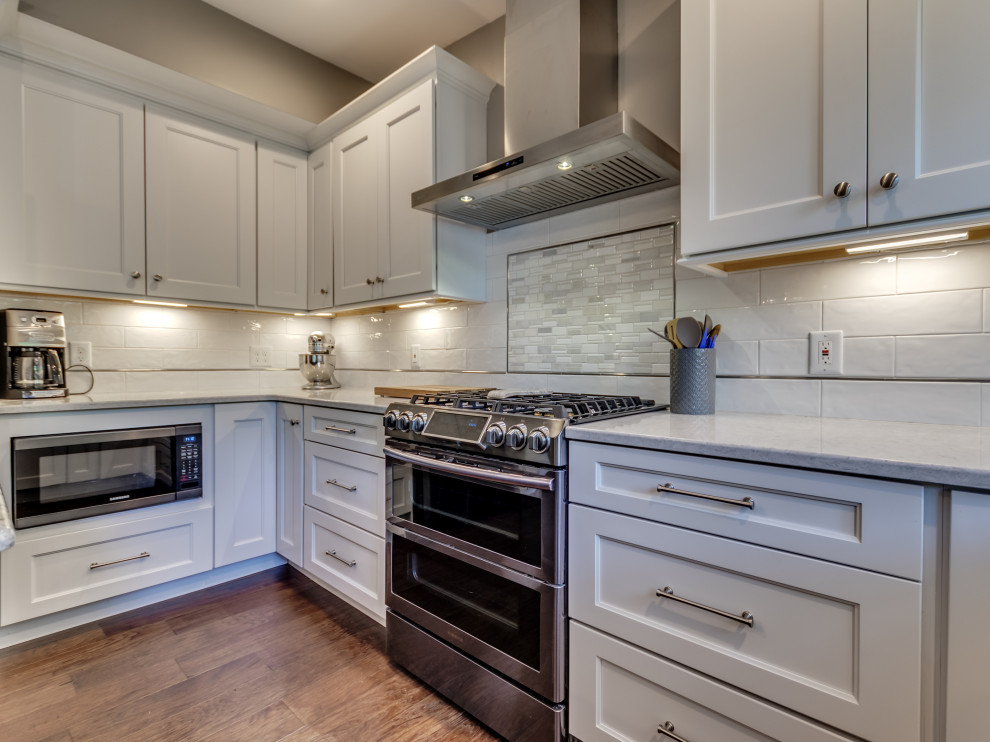 Eat-in kitchen - mid-sized transitional u-shaped brown floor eat-in kitchen idea in St Louis with white cabinets, white backsplash, subway tile backsplash, stainless steel appliances, an island, granite countertops and multicolored countertops