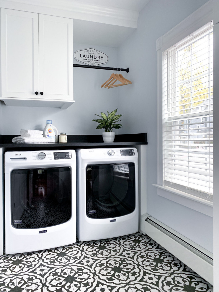 Klassisk inredning av en svarta svart tvättstuga enbart för tvätt, med skåp i shakerstil, vita skåp, granitbänkskiva, blå väggar, klinkergolv i porslin, en tvättmaskin och torktumlare bredvid varandra och svart golv