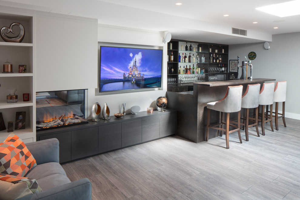Photo of a mid-sized transitional single-wall wet bar in London with flat-panel cabinets, black cabinets, grey floor, brown benchtop, mirror splashback and vinyl floors.