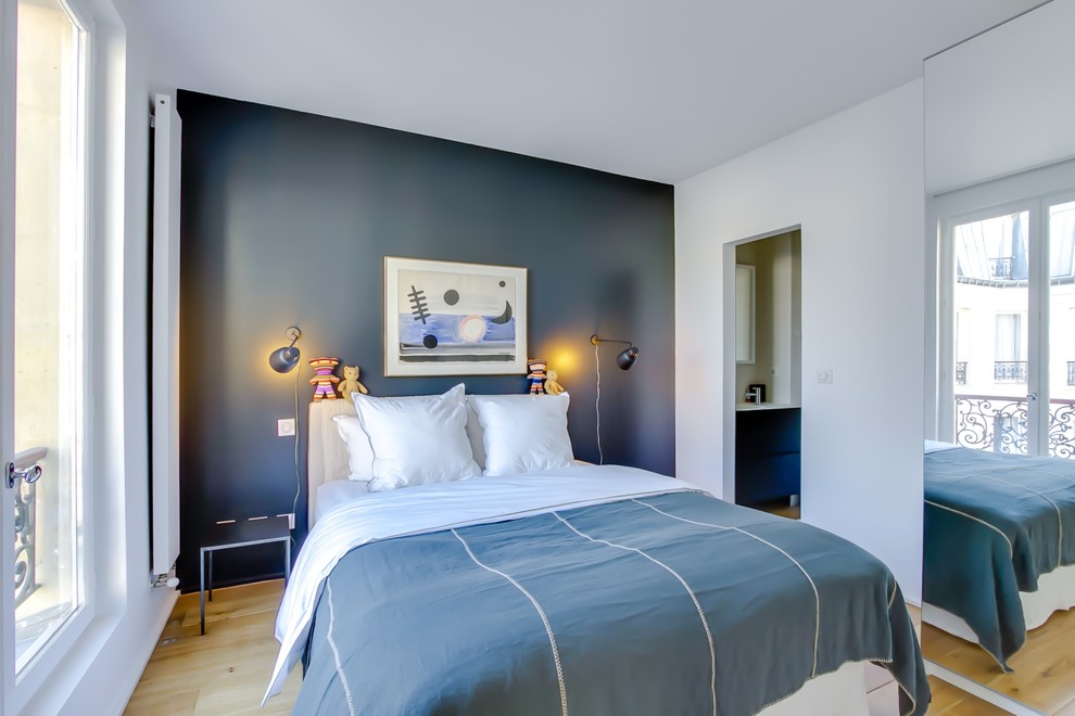 This is an example of a mid-sized transitional master bedroom in Paris with grey walls and light hardwood floors.