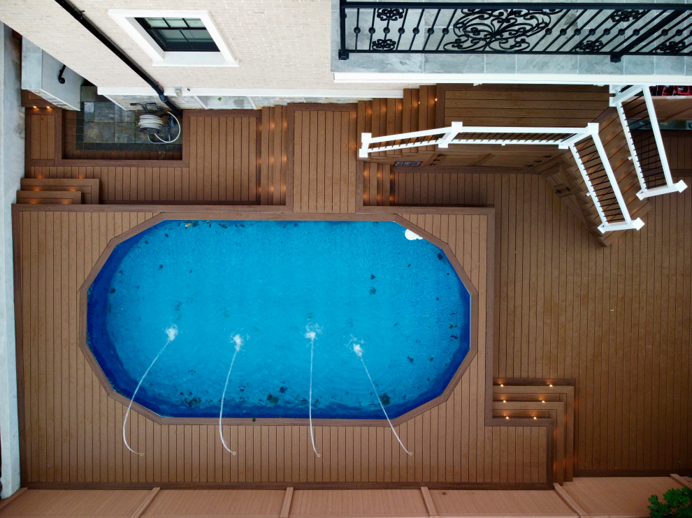 Example of a large classic backyard custom-shaped aboveground pool fountain design in New York with decking
