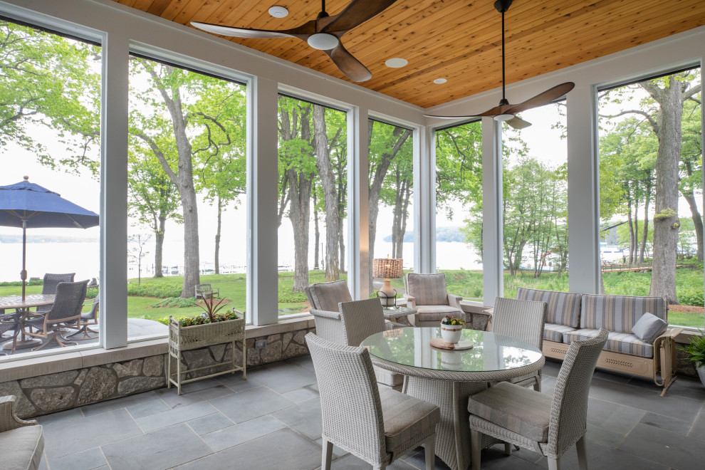 Inspiration for a mid-sized beach style backyard screened-in verandah in Milwaukee with natural stone pavers, a roof extension and mixed railing.