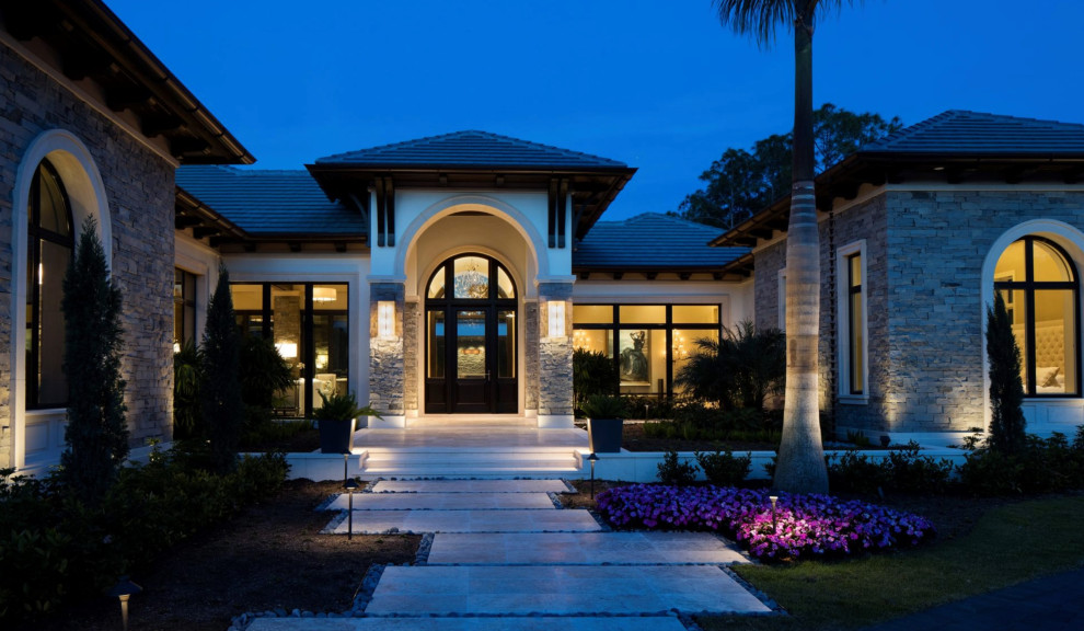 This is an example of a large tropical front door in Miami with a single front door, a glass front door and grey floor.