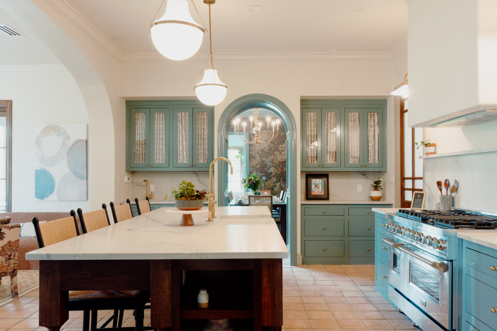 Transitional u-shaped terra-cotta tile and brown floor open concept kitchen photo in Austin with a farmhouse sink, glass-front cabinets, turquoise cabinets, marble countertops, white backsplash, marble backsplash, stainless steel appliances, an island and white countertops