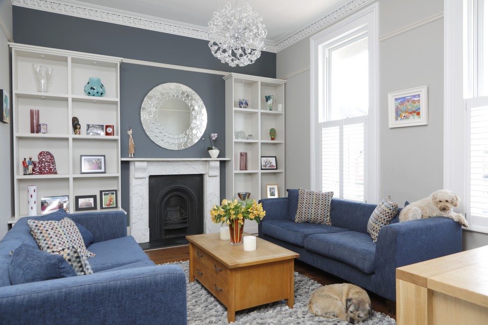 This is an example of a traditional formal living room in Gloucestershire with medium hardwood floors, a standard fireplace, a stone fireplace surround and grey walls.