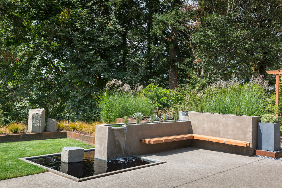 This is an example of a contemporary backyard garden in Portland with a water feature.