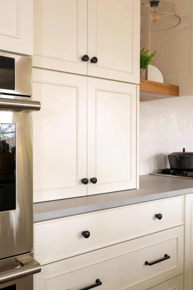 Large medium tone wood floor and exposed beam eat-in kitchen photo with white backsplash, stainless steel appliances and an island