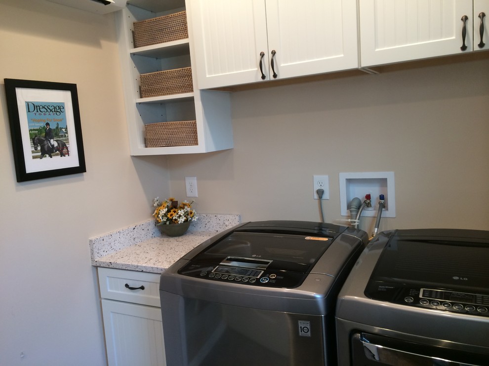 Photo of a small traditional galley dedicated laundry room in DC Metro with a single-bowl sink, beaded inset cabinets, white cabinets, beige walls, vinyl floors and a side-by-side washer and dryer.