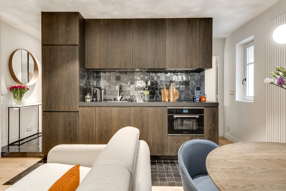 Photo of a mid-sized contemporary single-wall open plan kitchen in Paris with a single-bowl sink, dark wood cabinets, black splashback, terra-cotta splashback, panelled appliances, no island, beaded inset cabinets and terra-cotta floors.