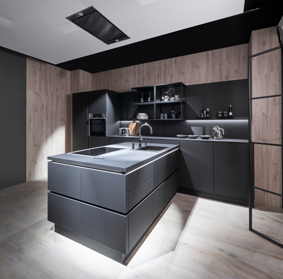 This is an example of a large modern single-wall kitchen in Melbourne with a drop-in sink, open cabinets, medium wood cabinets, laminate benchtops, black splashback, glass tile splashback, black appliances, with island and black benchtop.