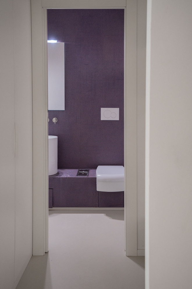 Diseño de aseo a medida minimalista pequeño con puertas de armario violetas, sanitario de una pieza, baldosas y/o azulejos en mosaico, paredes púrpuras, suelo de baldosas de cerámica, lavabo con pedestal, encimera de azulejos, suelo beige y encimeras moradas