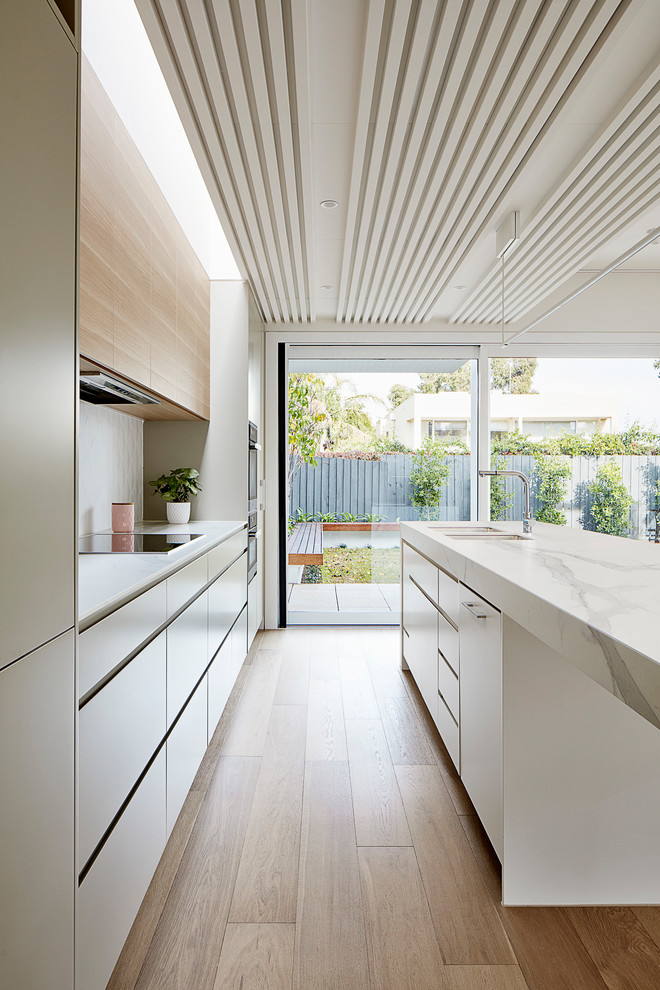 Inspiration for a contemporary galley kitchen in Melbourne with solid surface benchtops, ceramic splashback and with island.