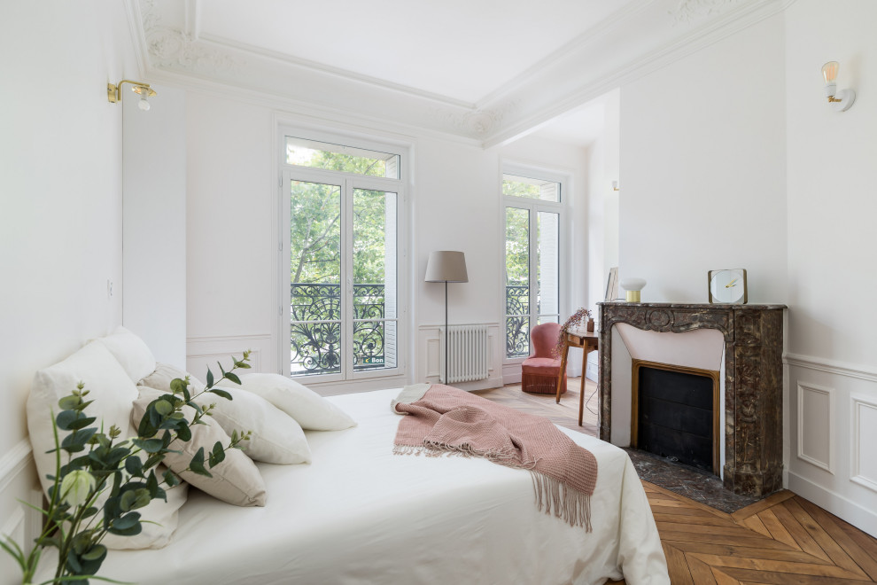 This is an example of a mid-sized contemporary guest bedroom in Paris with white walls, medium hardwood floors, a standard fireplace, brown floor and decorative wall panelling.