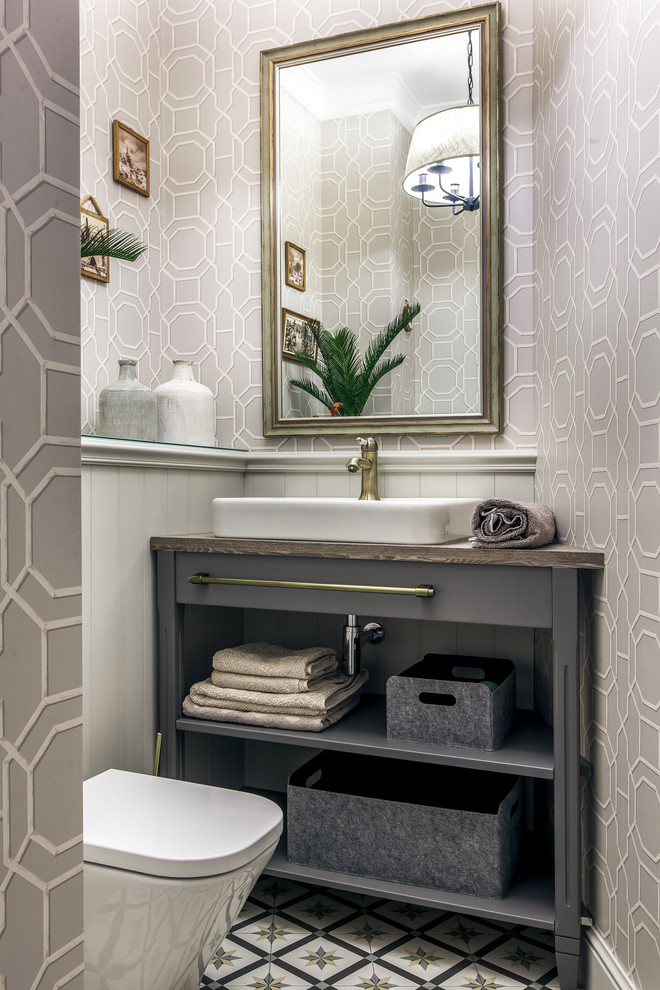 Photo of a small transitional powder room in Other with porcelain floors, laminate benchtops, open cabinets, grey cabinets, grey walls, a vessel sink, multi-coloured floor and grey benchtops.