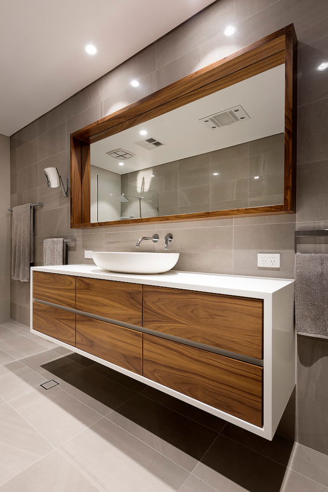 This is an example of a mid-sized modern master bathroom in Perth with flat-panel cabinets, medium wood cabinets, a freestanding tub, an open shower, brown tile, travertine, brown walls, ceramic floors, a vessel sink, engineered quartz benchtops, brown floor, an open shower, white benchtops, a shower seat, a single vanity, a floating vanity and vaulted.
