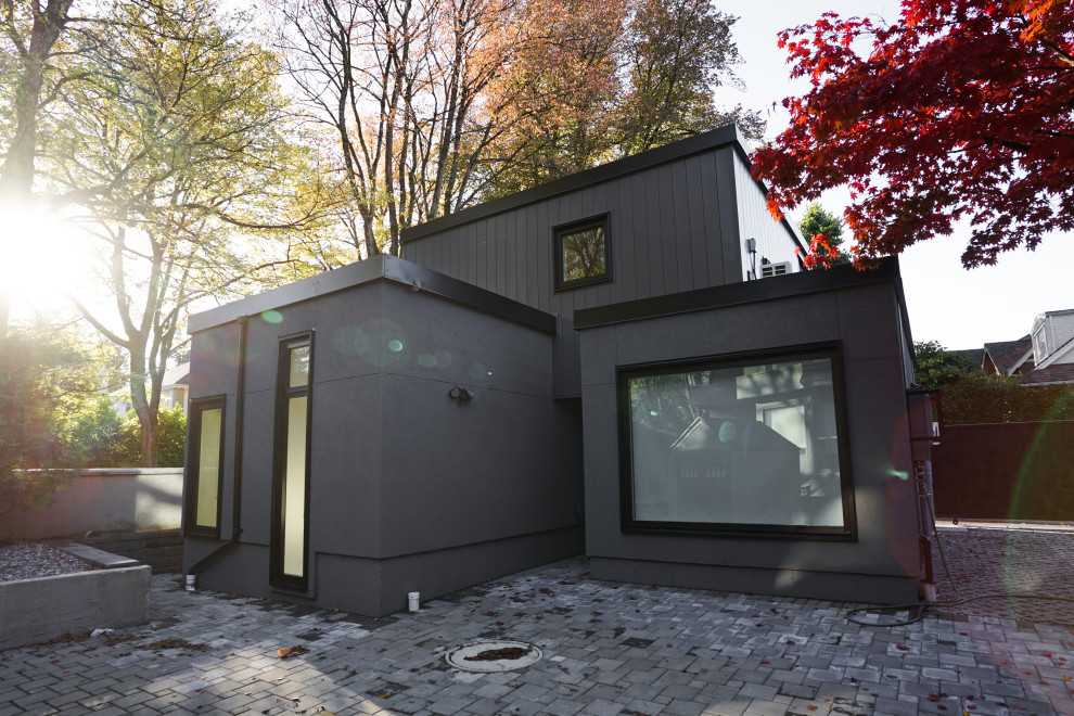 Cette photo montre une petite façade de Tiny House métallique et noire à un étage avec un toit plat, un toit en métal et un toit noir.