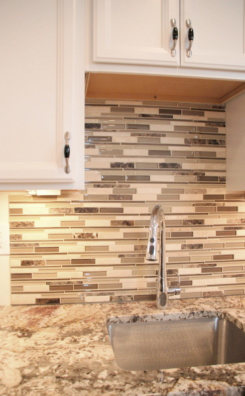 Example of a small transitional l-shaped open concept kitchen design in Detroit with an undermount sink, recessed-panel cabinets, white cabinets, quartz countertops, multicolored backsplash, glass tile backsplash and black appliances